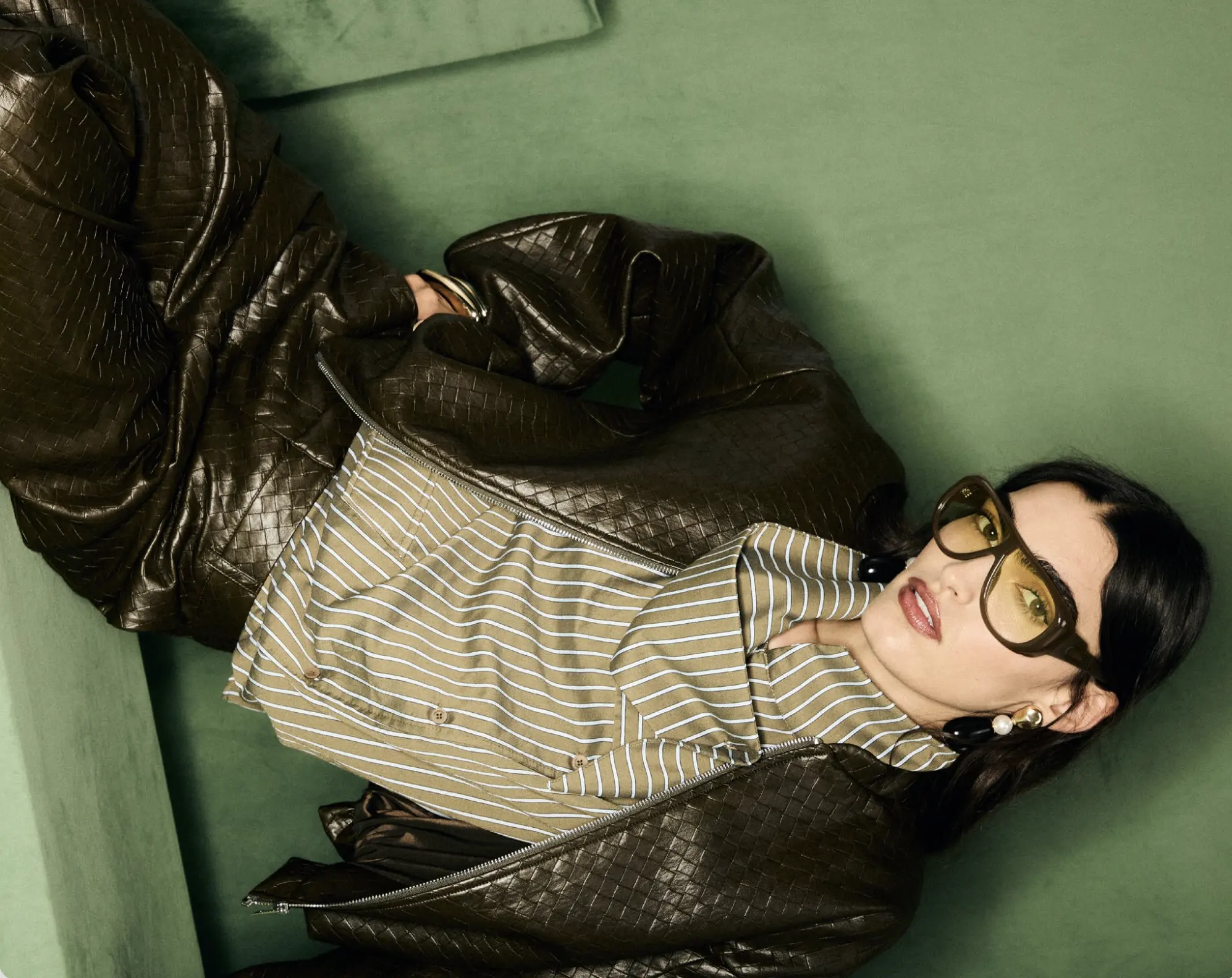 Model in geflochtener Lederjacke und gestreiftem Hemd mit getönter Brille – italienische Mode für Boutiquen